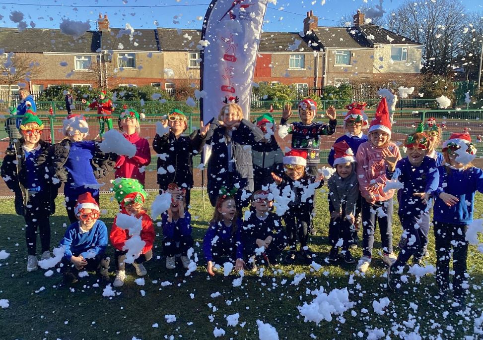 Class posing for a photograph with a snow machine.