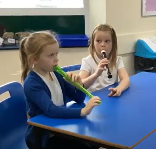 Two children playing recorder. 