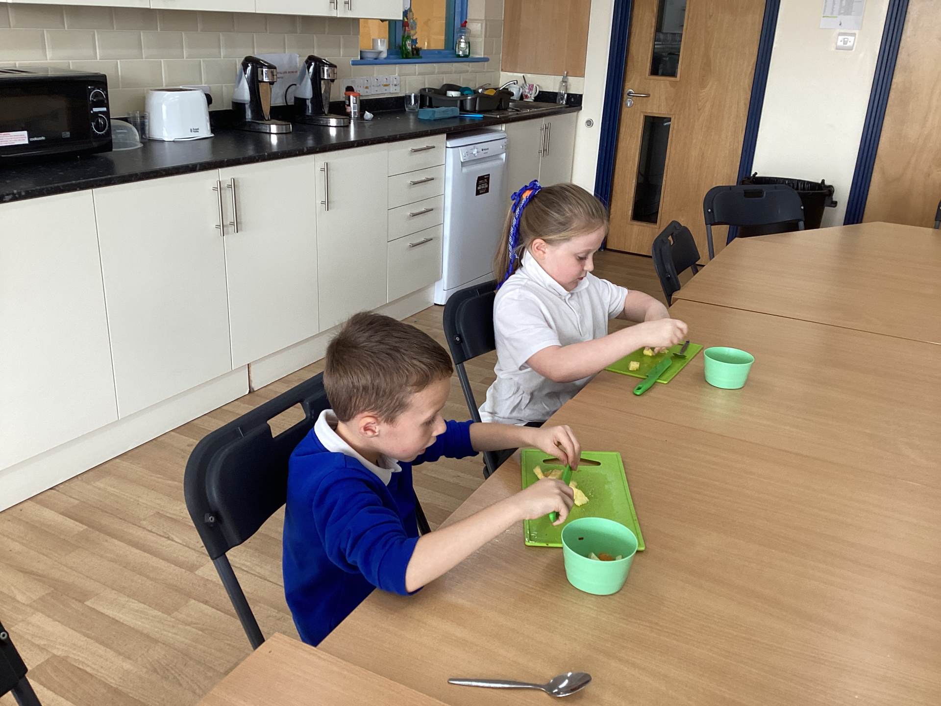 Two children cutting up some fruit.