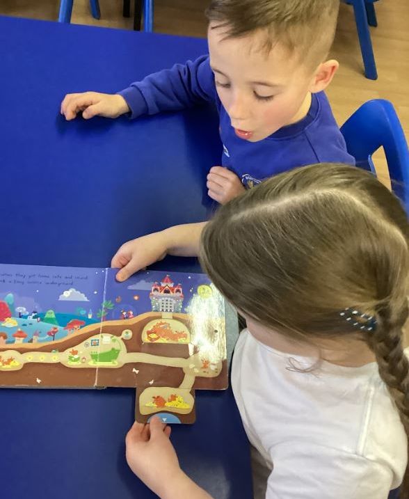 Two children pulling a slider out from the side of the book to see what it says.